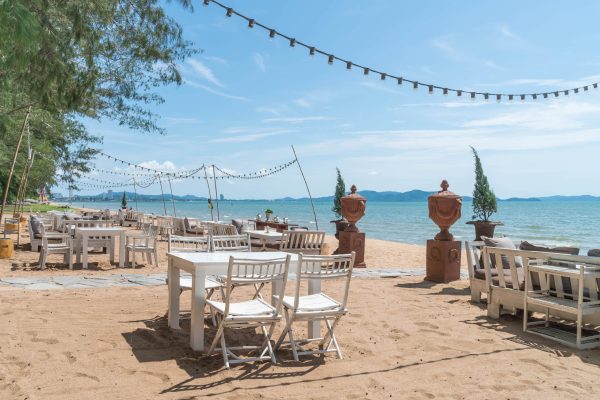 white-chairs-table-beach-with-view-blue-ocean-clear-sky-min