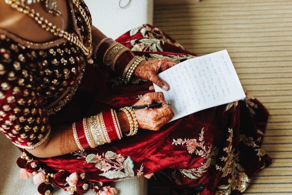 Bride in traditional indian clothes is writting her vows on the paper