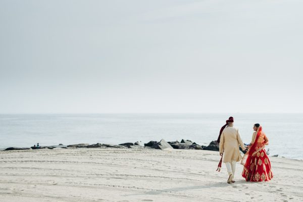 hindu-wedding-couple-walks-along-ocean-shore-min